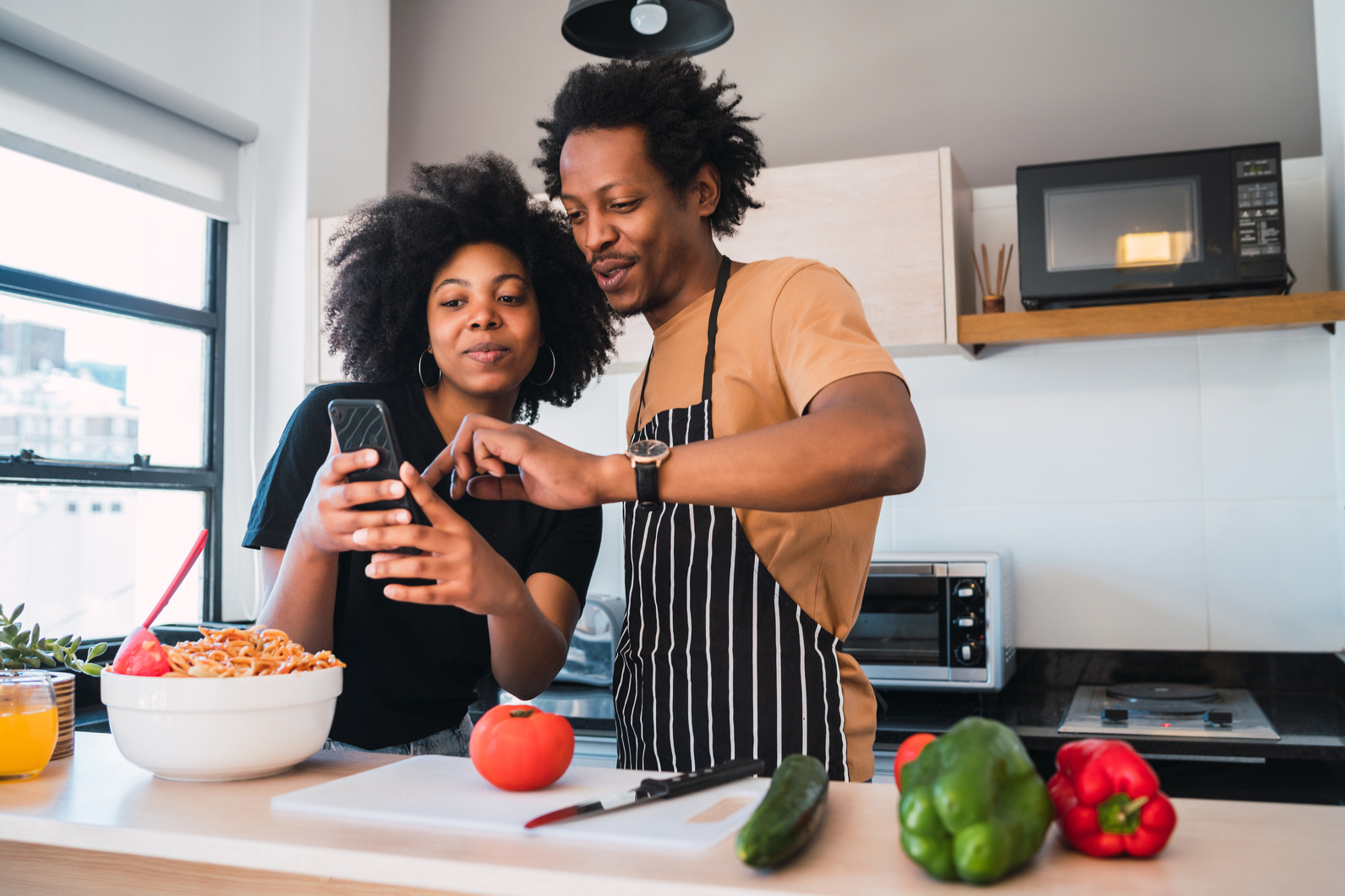 Afro Couple Cooking Together and Using Phone at Home.